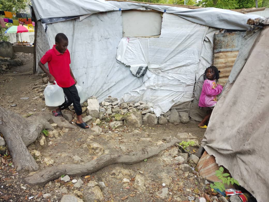 Haitian child carrying water containers